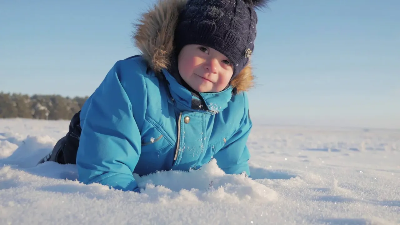 dziecko w zestawie kurtka i spodnie narciarskie bawi się