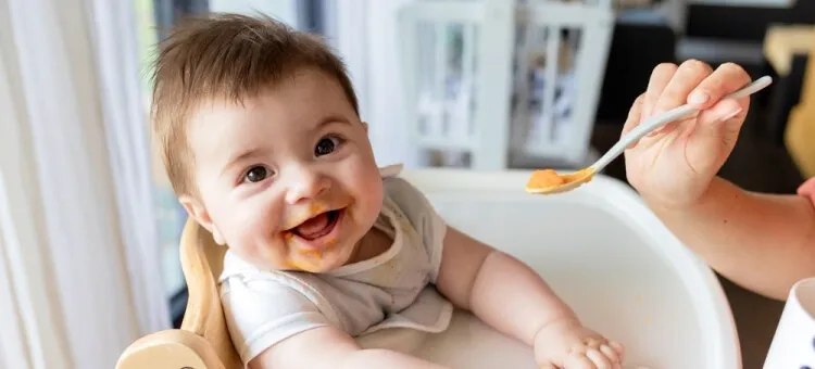 Rodzic karmiący niemowlę kaszką łyżeczką