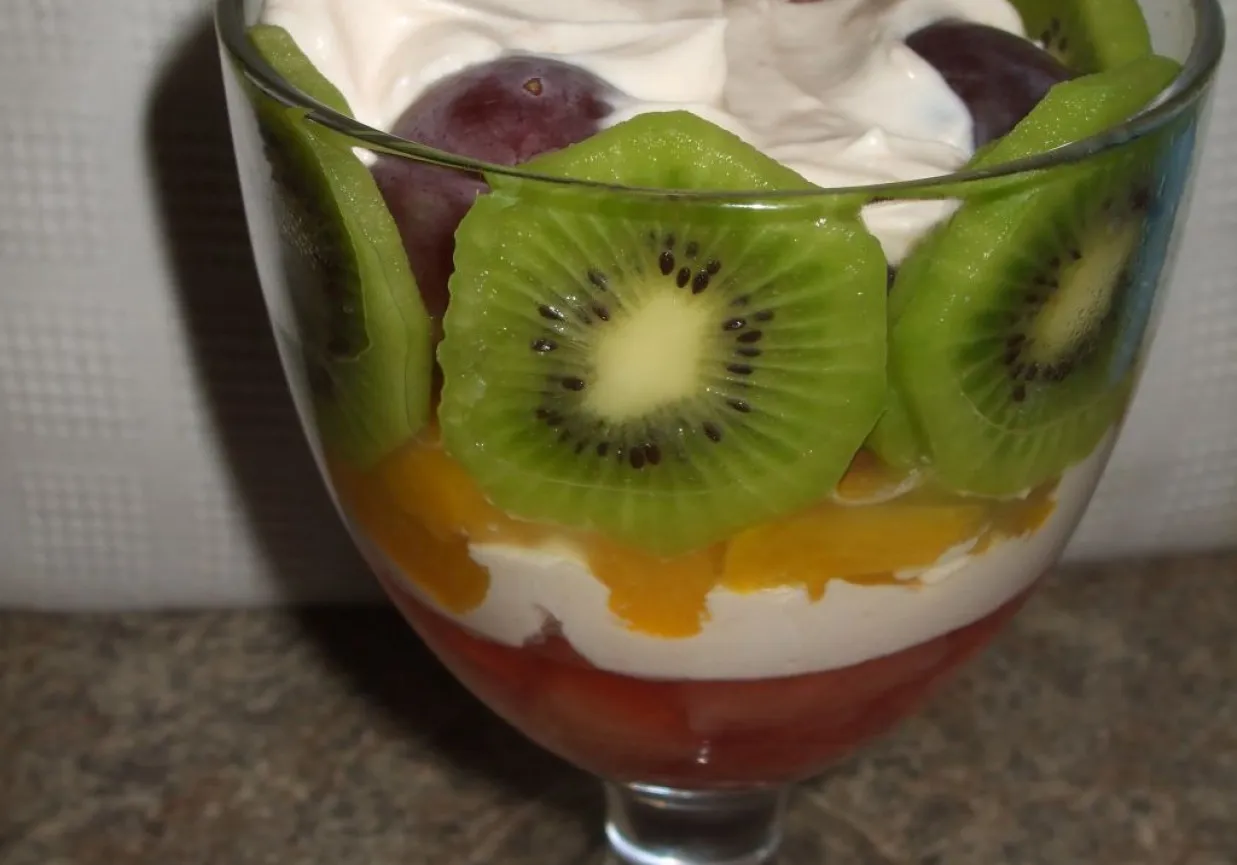Warstwowy deser w pucharku: galaretka, krem, brzoskwinie, kiwi i winogrona. Idealne dodatki do galaretki owocowej.