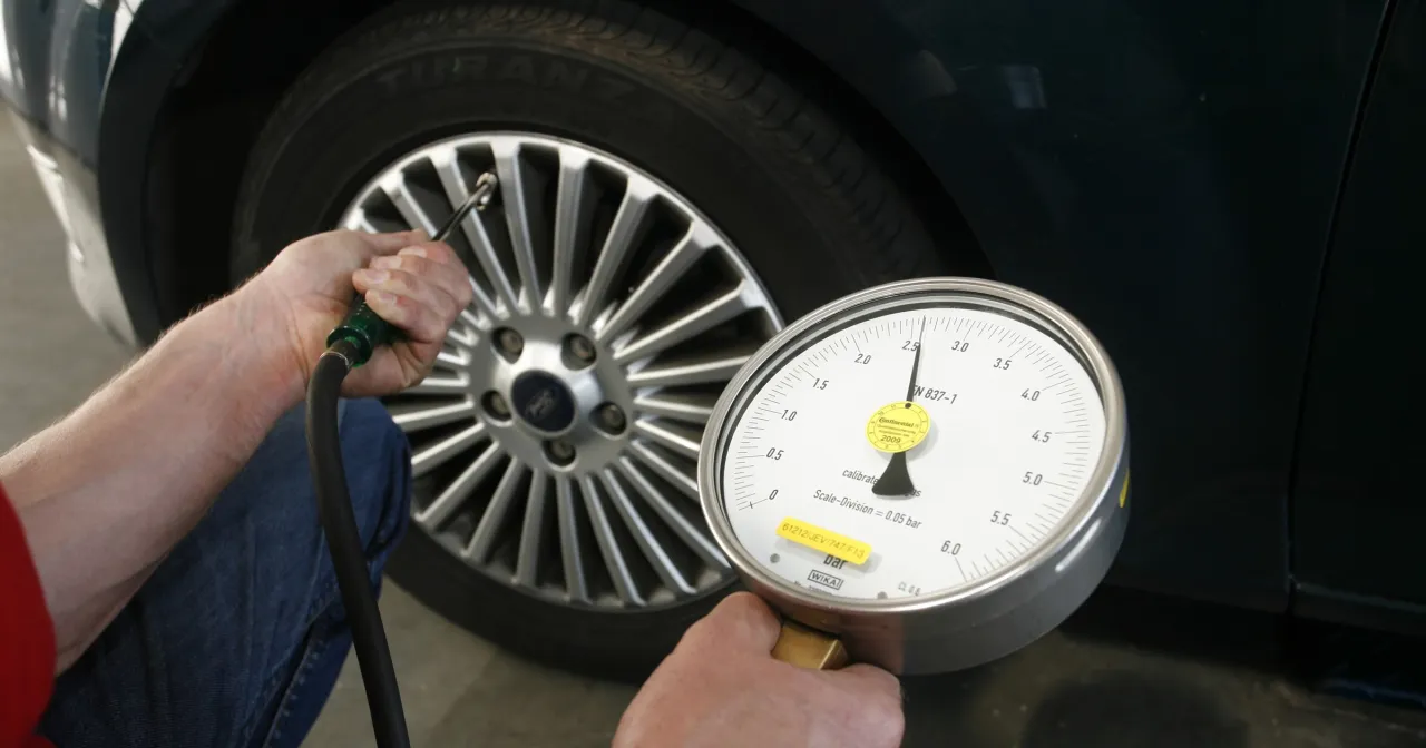kierowca mierzący ciśnienie w oponie zimą, manometr