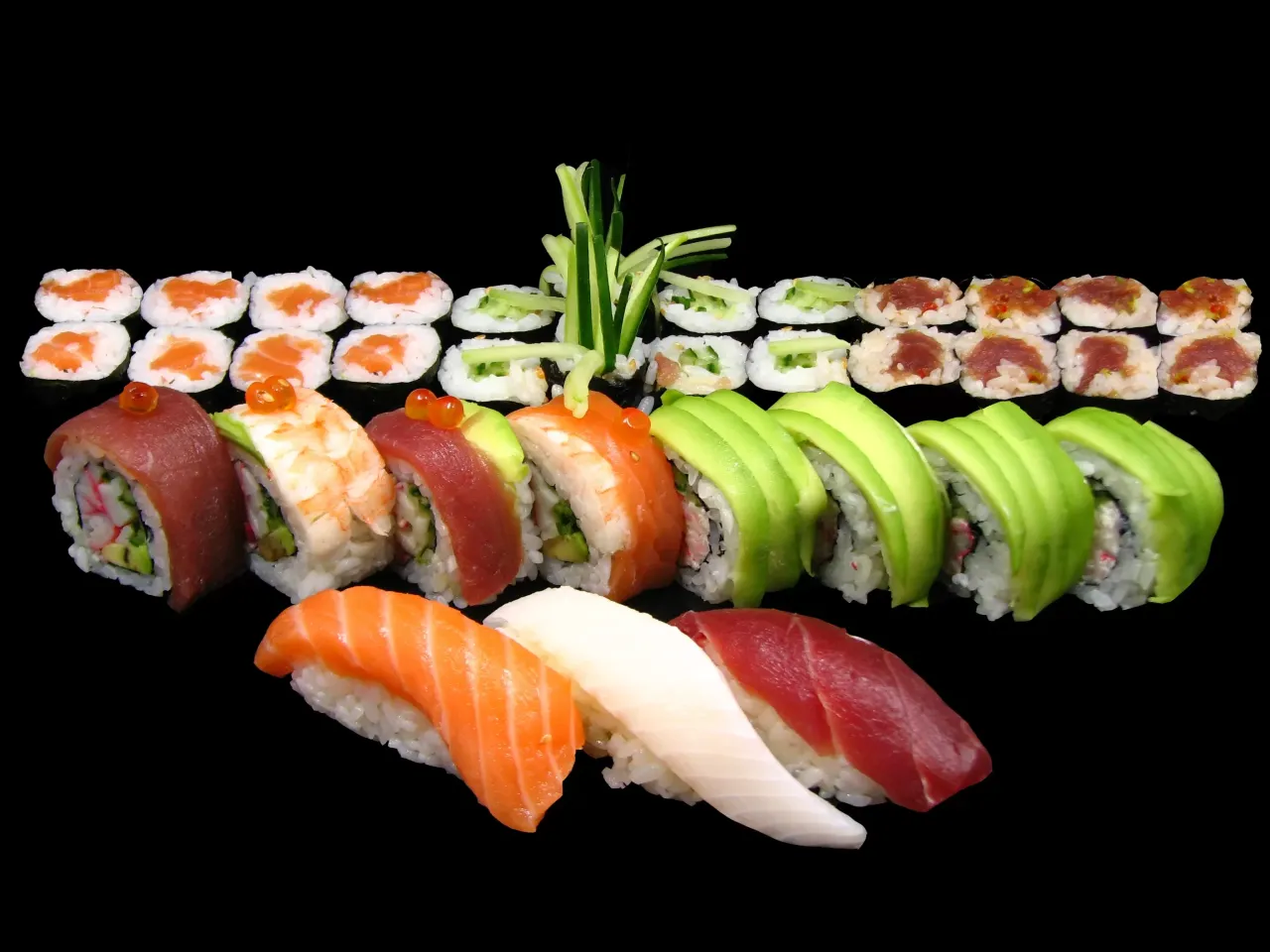 R&oacute;żnorodne sushi: nigiri z łososiem, tuńczykiem i kalmarem, rolki z awokado, krewetką, tuńczykiem i og&oacute;rkiem. Idealne na początek nauki, jak jeść sushi.