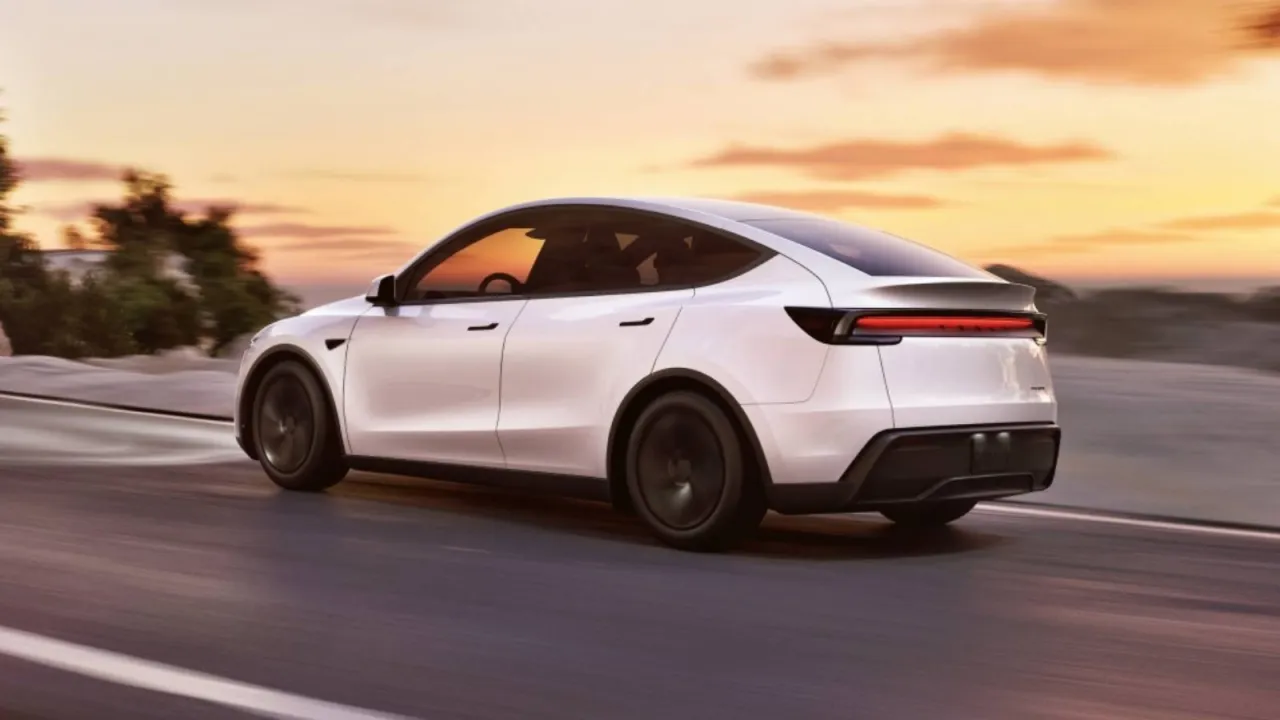 Biała Tesla Y pędzi po drodze o zachodzie słońca. Zastanawiasz się, ile koni ma ten model?
