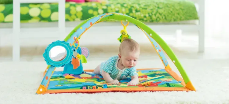 niemowlę na kolorowej macie edukacyjnej z zabawkami