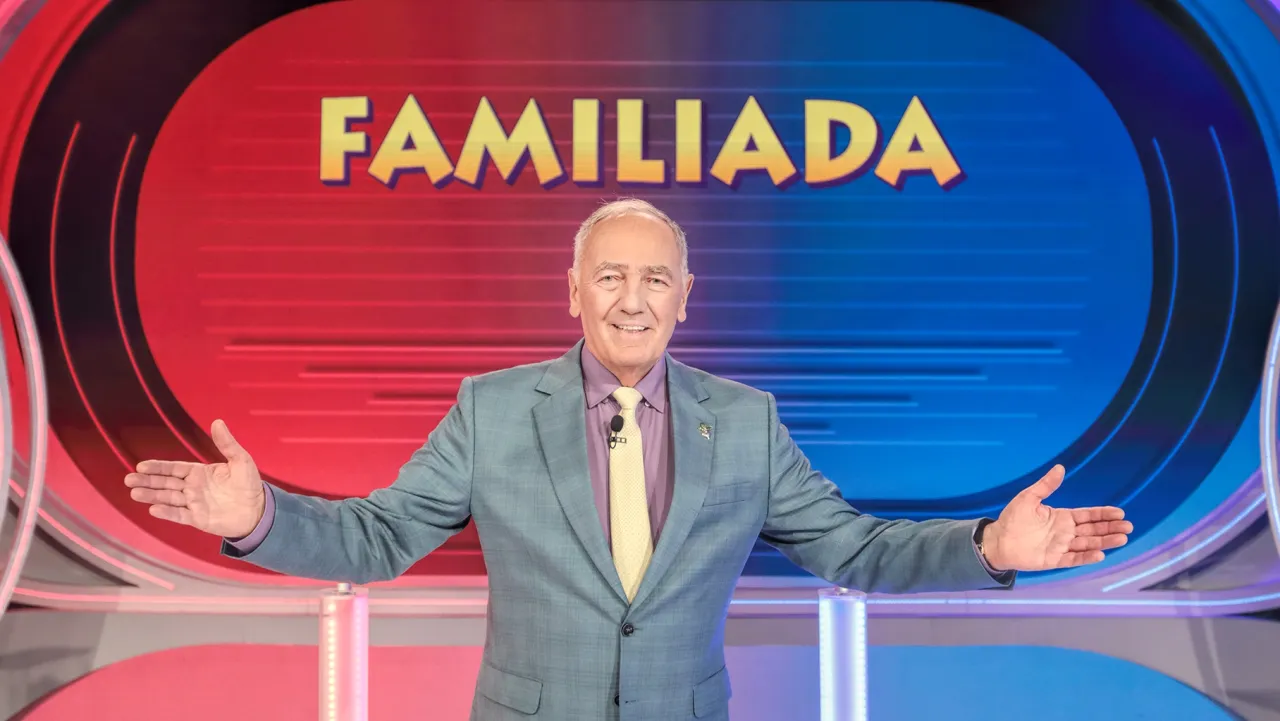 Uśmiechnięty mężczyzna w garniturze, kt&oacute;ry prowadzi Familiadę.