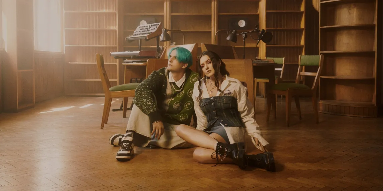 Para siedzi na podłodze w bibliotece. On ma zielone włosy, ona wisiorek. Kto śpiewa dzięki że jesteś?