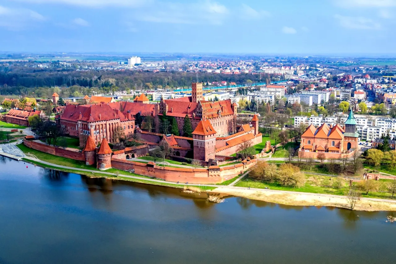Zamek w Malborku i okolice co zwiedzić: potężna twierdza krzyżacka nad rzeką, wspaniałe miasto i lasy.