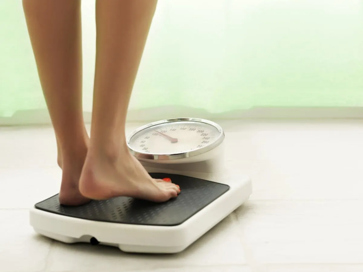 osoba ważąca się na wadze z miną frustracji