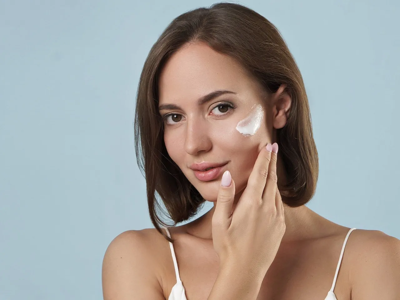 Kobieta nakładająca serum na wilgotną sk&oacute;rę twarzy