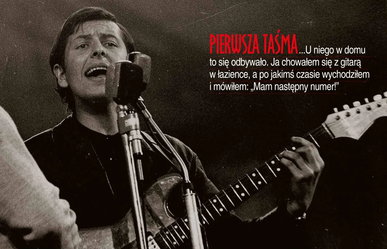 Młody muzyk z gitarą i mikrofonem, śpiewający fragment tekstu piosenki kiedy byłem małym chłopcem.