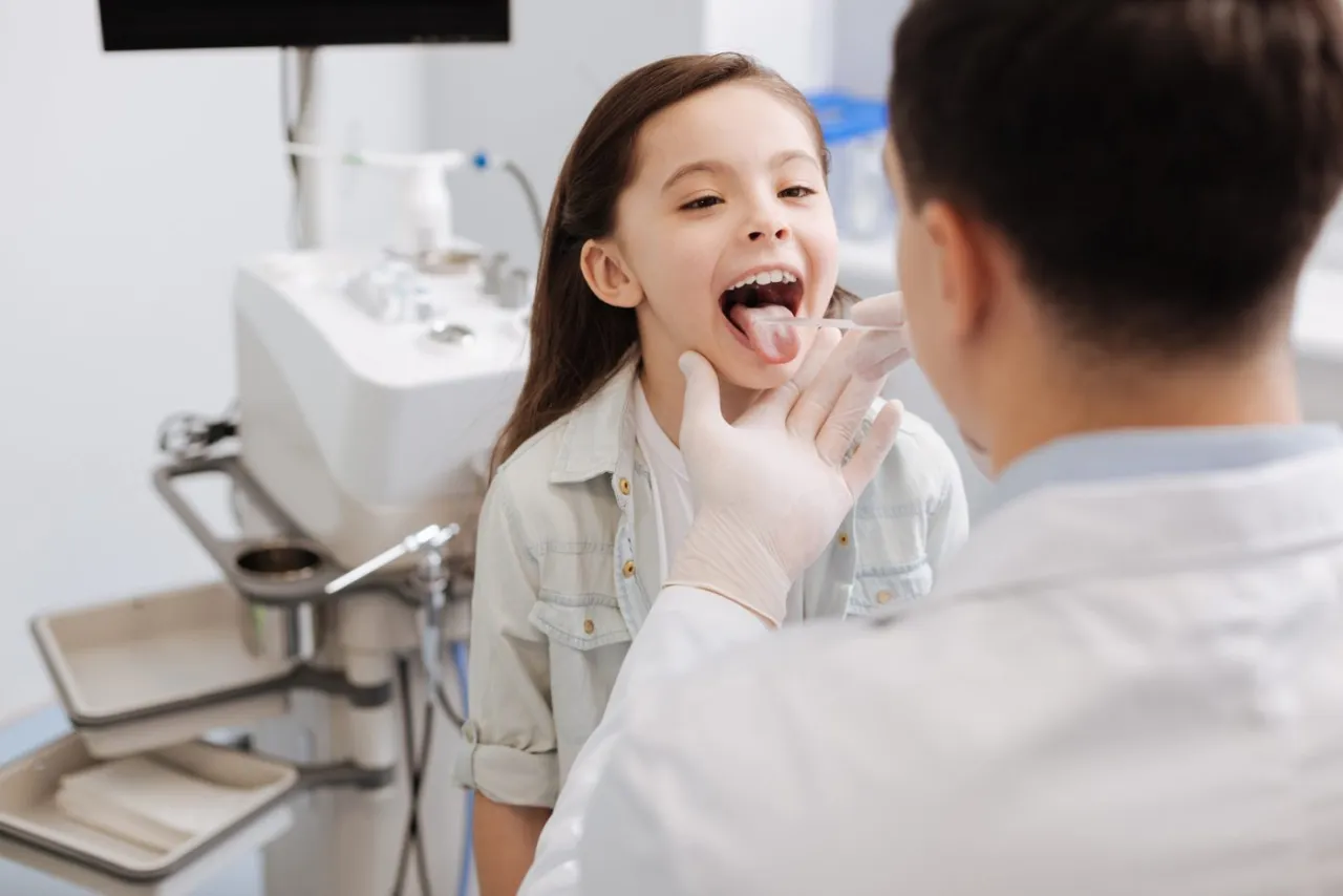 Lekarz bada gardło dziecka