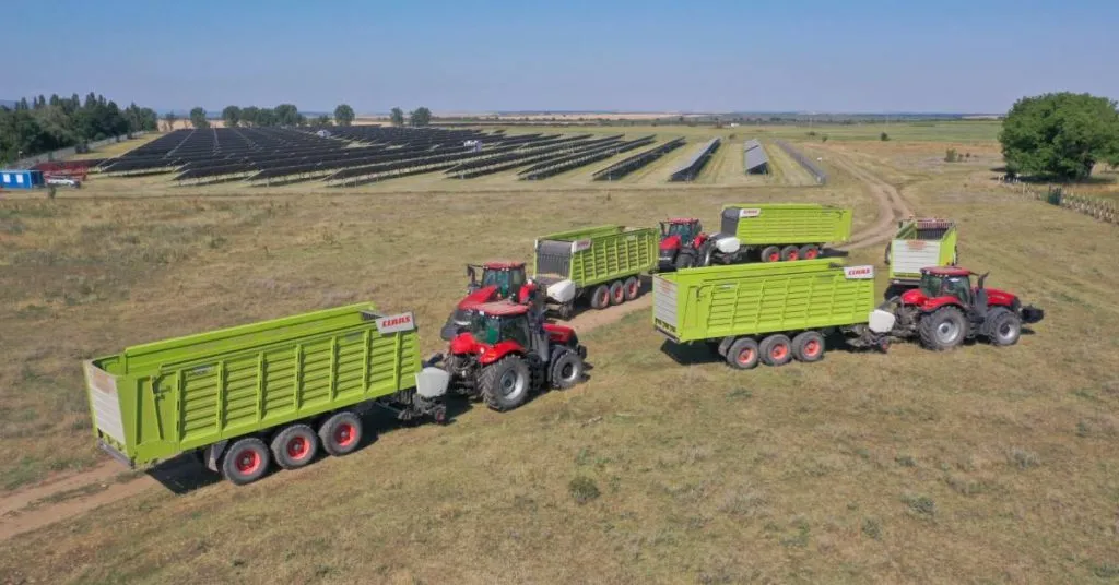 Rolnik na tle pola z panelami fotowoltaicznymi i traktorem
