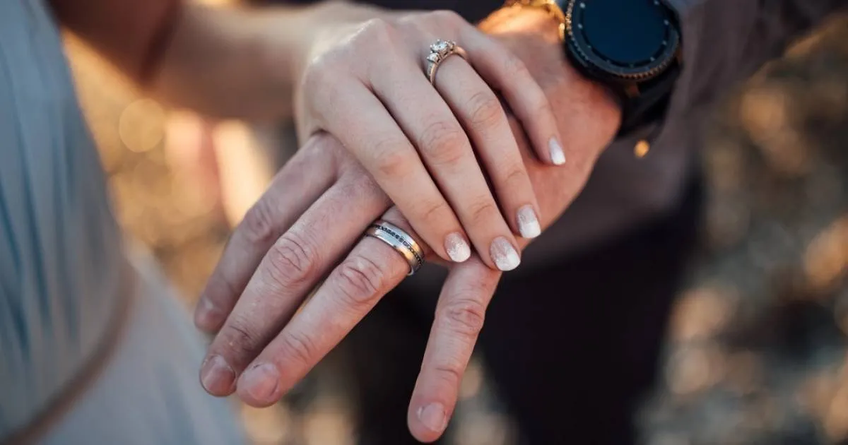 para starszych ludzi trzymająca się za ręce z rubinowym pierścionkiem na palcu