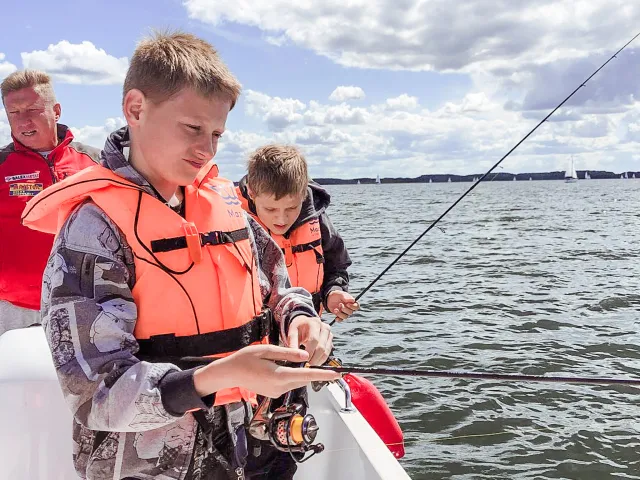 młodzi wędkarze z opiekunem nad wodą