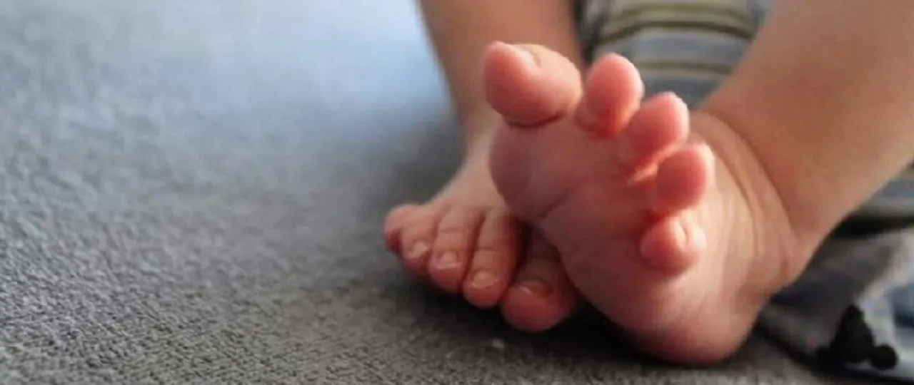 Małe stópki dziecka na szarym tle. Zastanawiasz się, jak przemeldować dziecko? To proste, gdy masz już te małe nóżki!