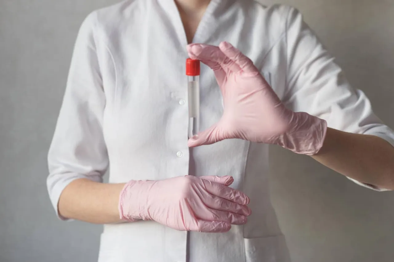 Lekarz w różowych rękawiczkach trzyma probówkę. Zastanawiasz się, ile kosztuje wizyta u urologa prywatnie?