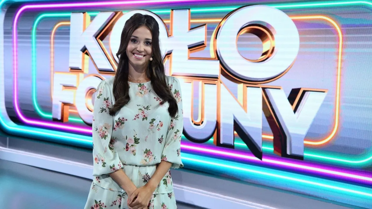 Uśmiechnięta prowadząca na tle neonowego napisu 