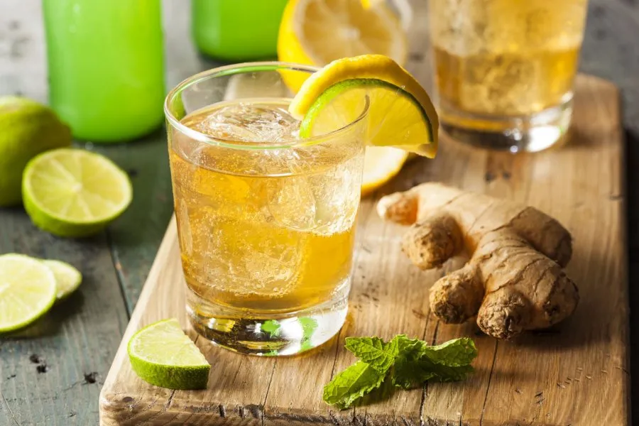 Person mixt Cocktails mit Ginger Ale und frischen Zutaten