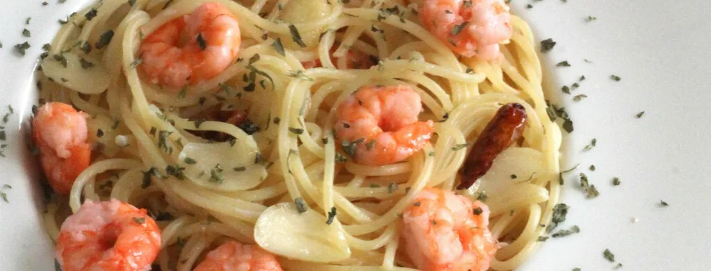 espaguetis al ajillo con gambas en un plato blanco