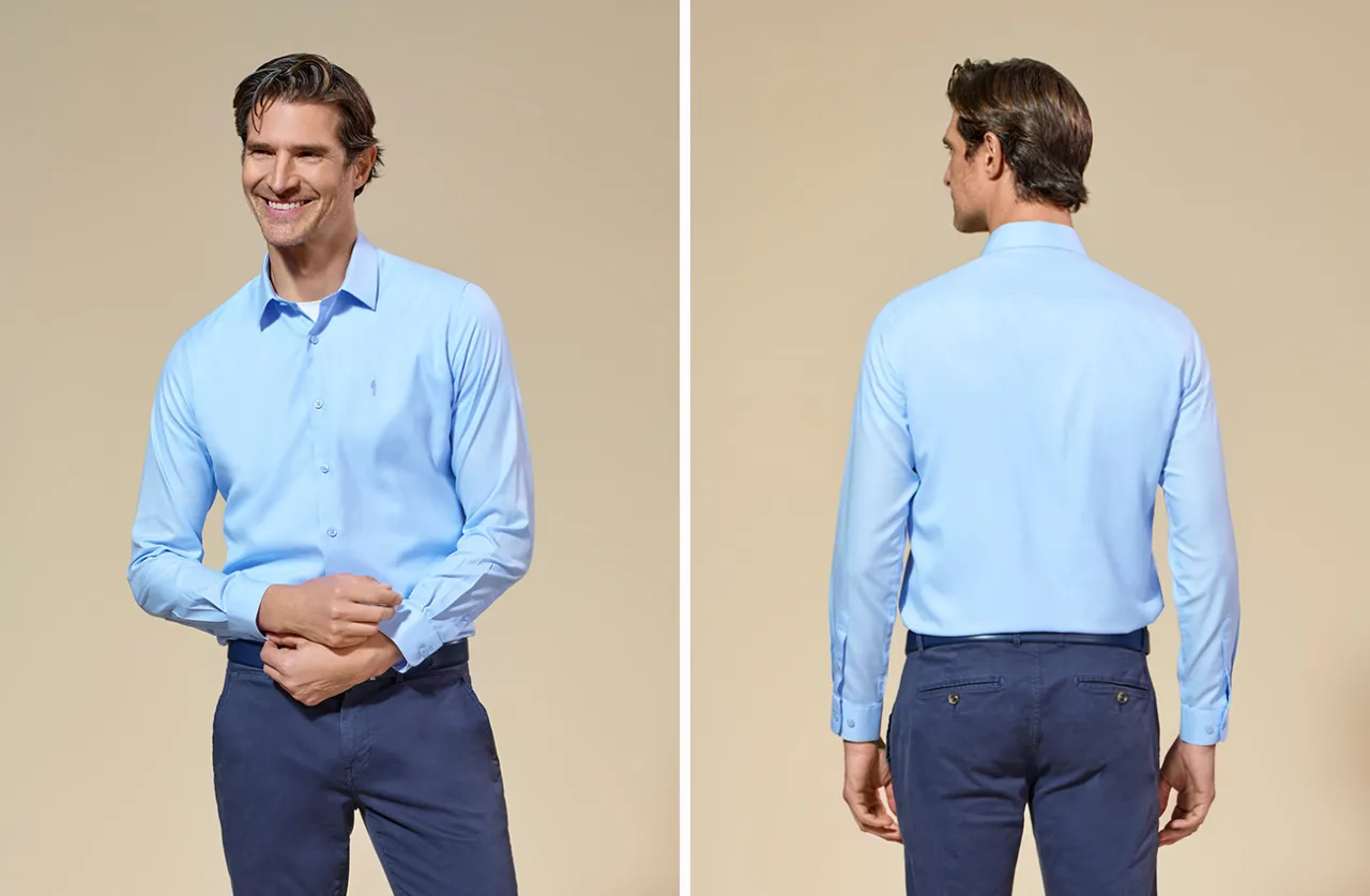 Mężczyzna w błękitnej koszuli i granatowych spodniach. Czy koszula w spodnie, czy nie &ndash; wygląda elegancko.