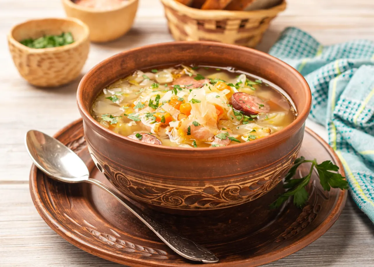 Pyszny kapuśniak ze świeżej kapusty z kiełbasą i warzywami, podany w glinianej misce. Idealny na chłodne dni.