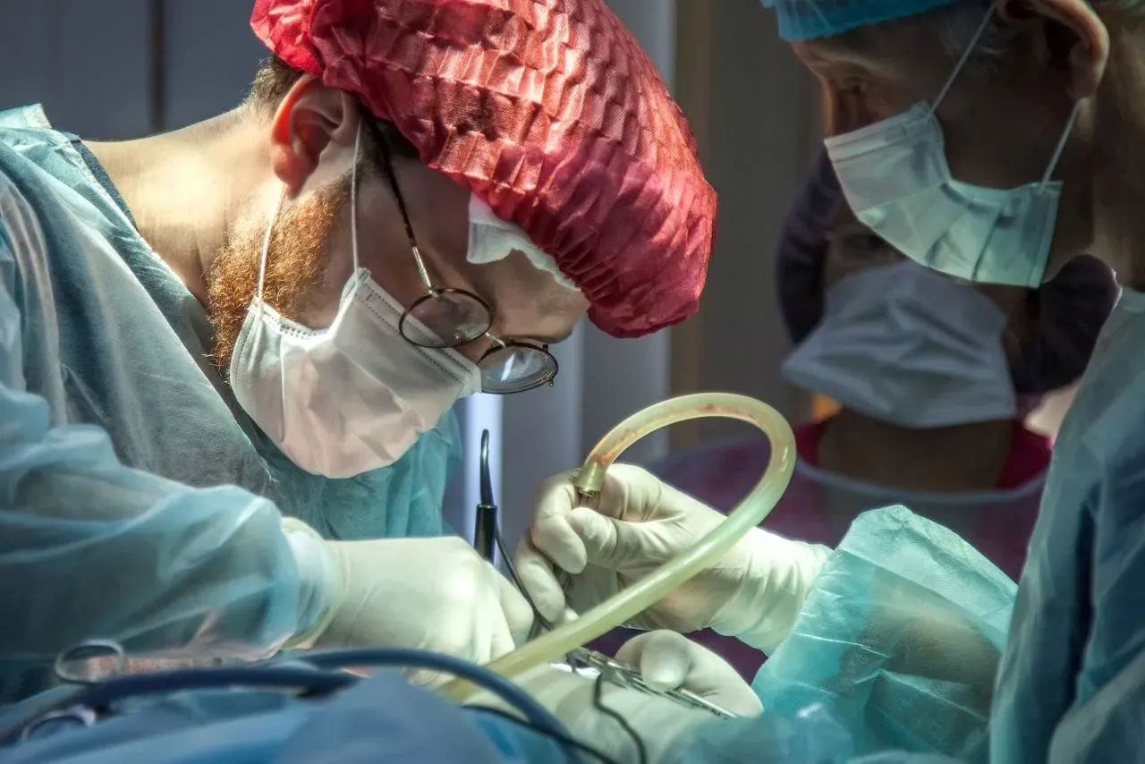Chirurdzy w maseczkach i rękawiczkach pracują przy pacjencie. Warto wiedzieć, jakie odszkodowanie za operacje przysługuje w razie powikłań.