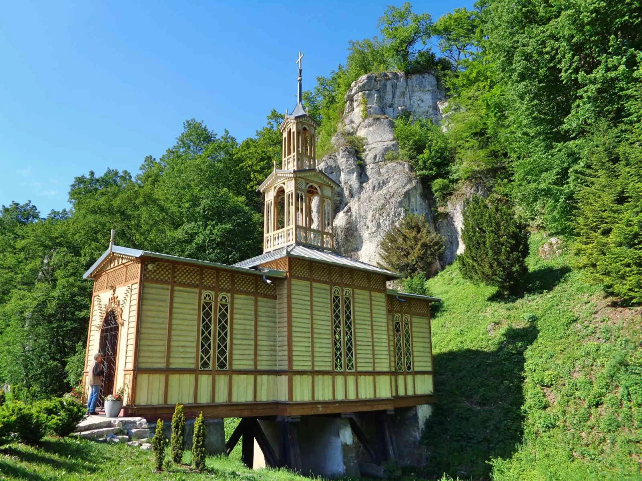 Drewniana kapliczka na skale, idealne miejsce na postój podczas podróży ojców trasą rowerową.