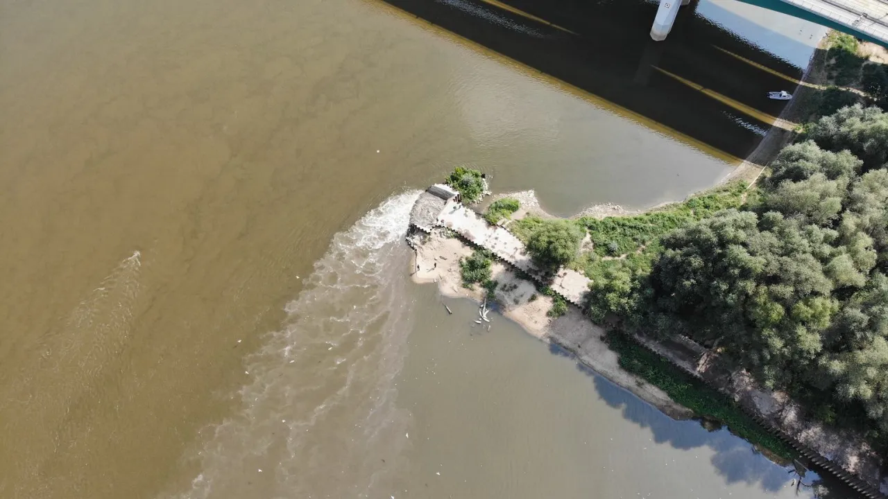 Woda z oczyszczalni Czajka wpływa do Wisły. Co dalej z oczyszczalnią? Widać most i zielone brzegi rzeki.