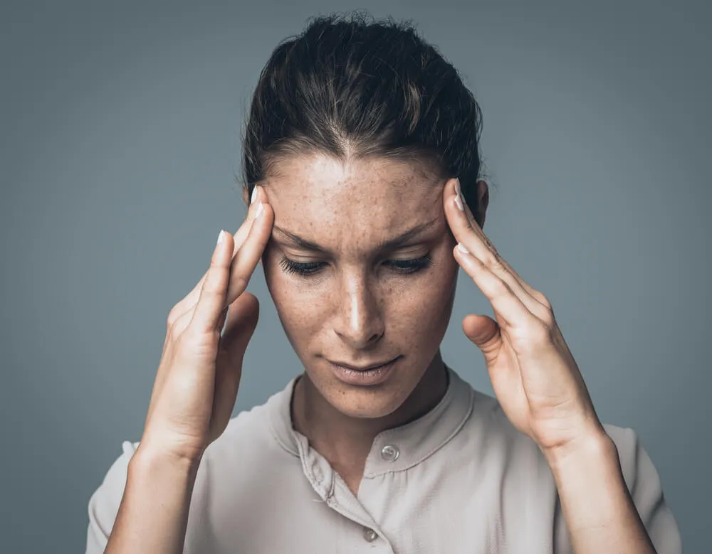 Osoba z bólem głowy, trzymająca się za skronie