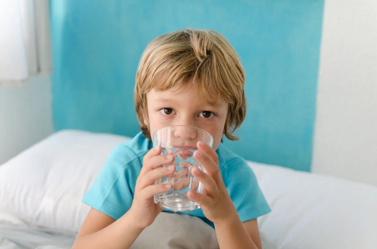 Dziecko pije wodę, rodzic robi chłodne okłady, nawadnianie dziecka przy gorączce