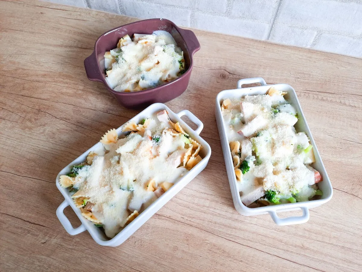 Pyszna zapiekanka makaronowa z serem, brokułami i kurczakiem w trzech naczyniach.