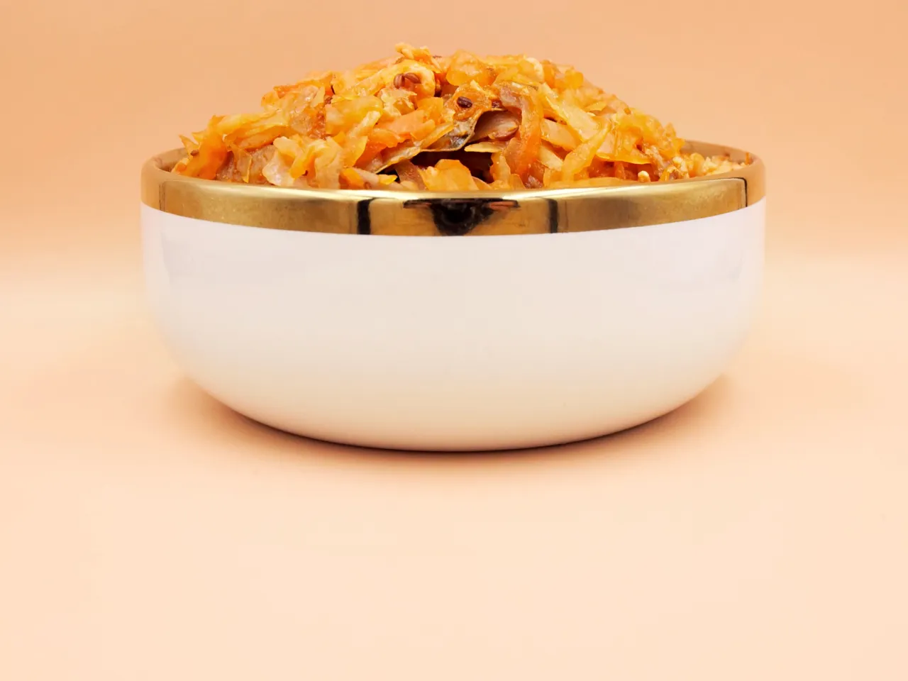 Misternie przygotowany bigos z kiszonej kapusty w białej miseczce ze złotym rantem. Zastanawiasz się, ile kalorii ma bigos z kiszonej kapusty?