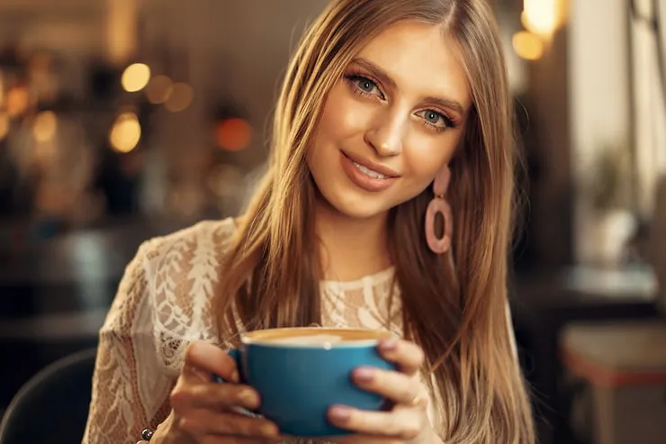 kobieta pijąca kawę z mlekiem sojowym uśmiechnięta