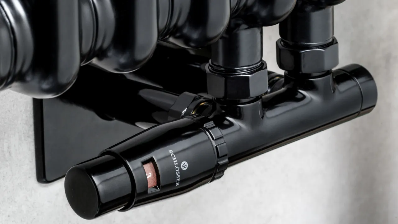 Czarny zawór termostatyczny grzejnika z widocznym pokrętłem i oznaczeniem