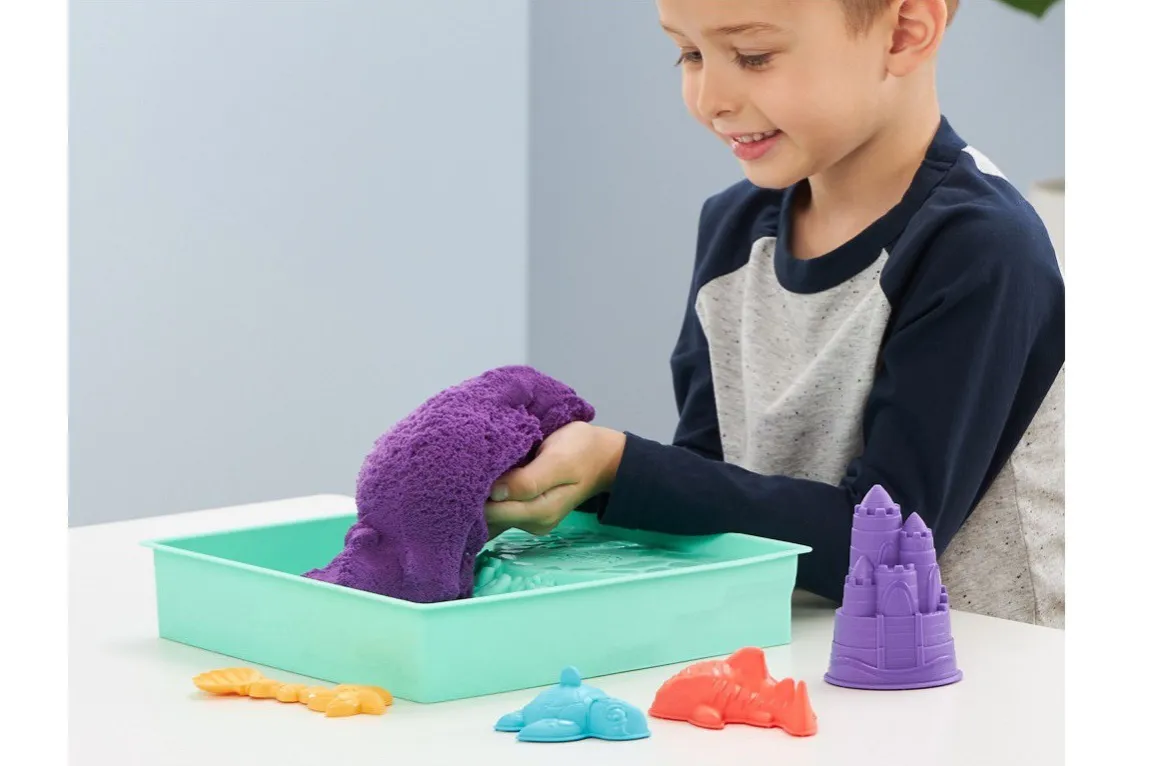 dziecko bawiące się piaskiem kinetycznym w pojemniku sensorycznym