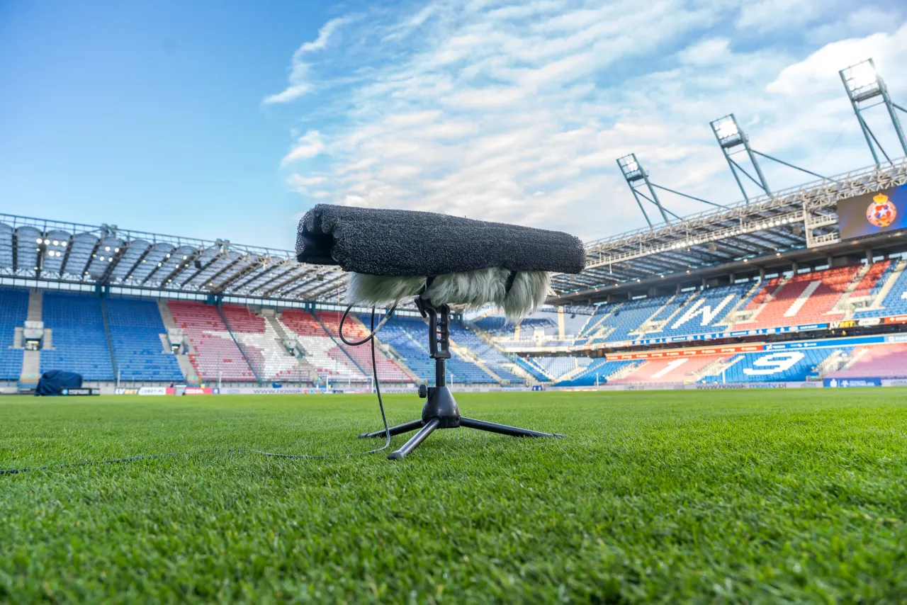 Mikrofon na statywie na pustym stadionie, gotowy do nagrania dźwięk&oacute;w, kto dziś gra w piłkę nożną.
