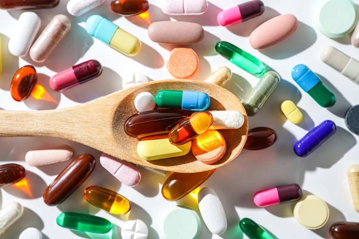 Wiele tabletek i kapsułek na drewnianej łyżce. Czy leki dla seniorów są za darmo?