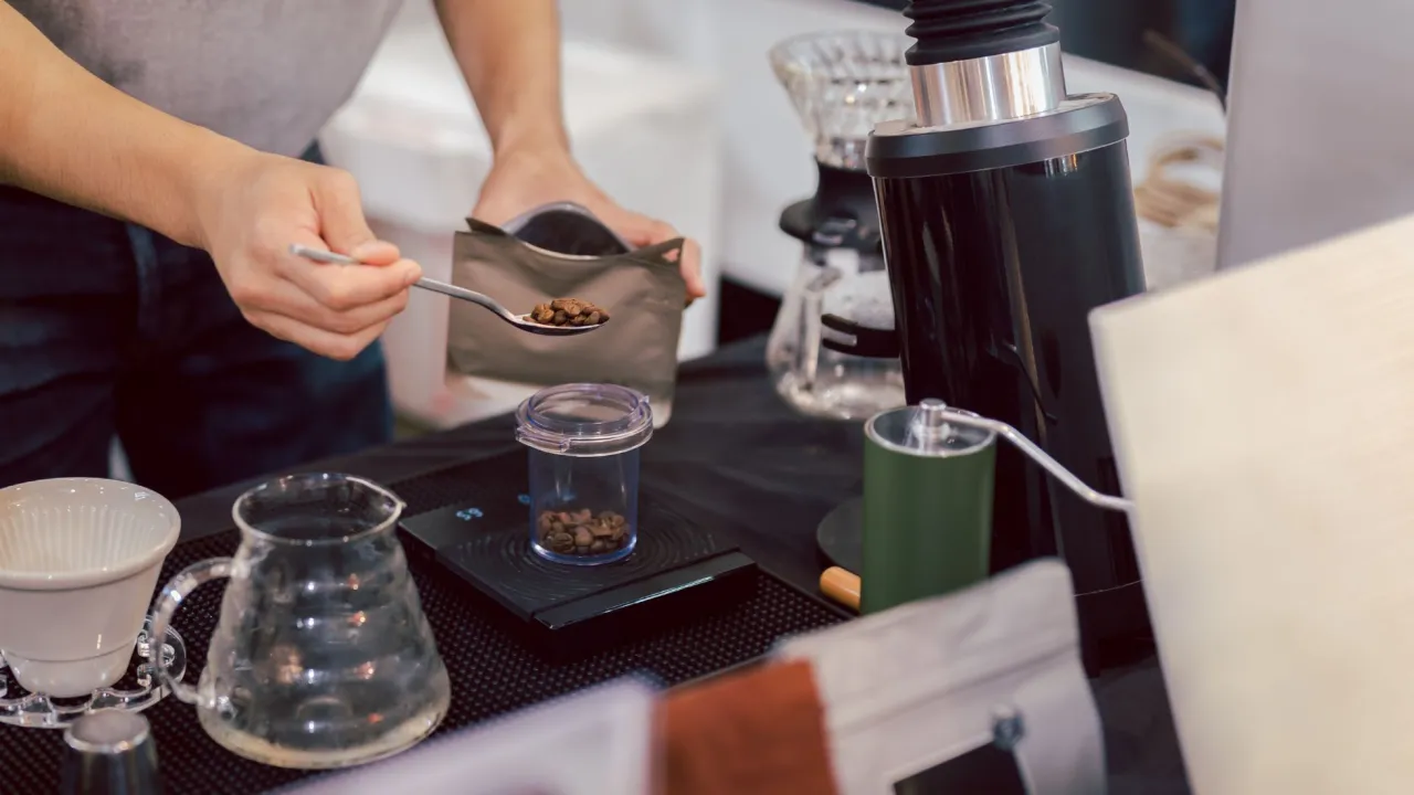 Przygotowanie kawy, by wiedzieć, ile kofeiny przed treningiem. Odmierza ziarna na łyżeczce.