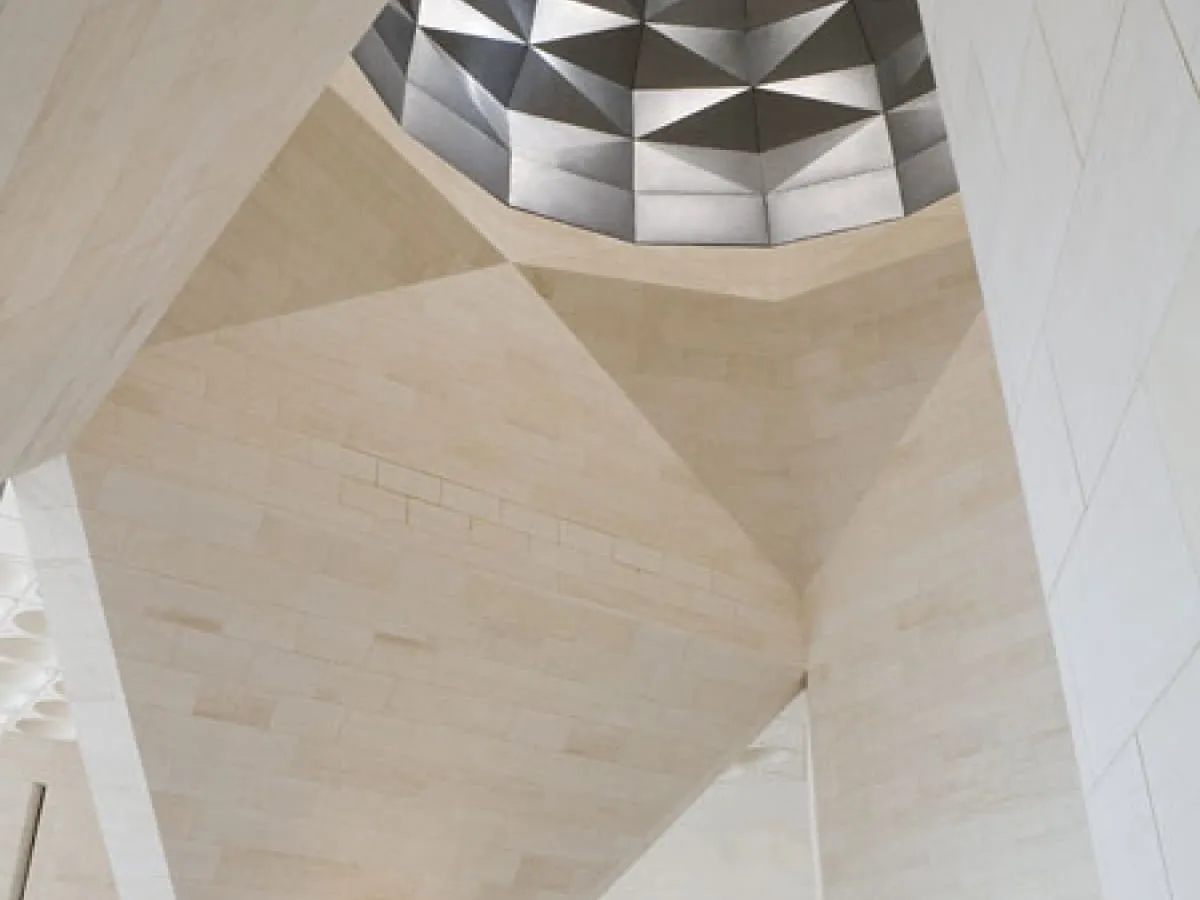 Geometryczne sklepienie w muzeum sztuki islamskiej, z kamiennymi panelami i metalową kopułą.