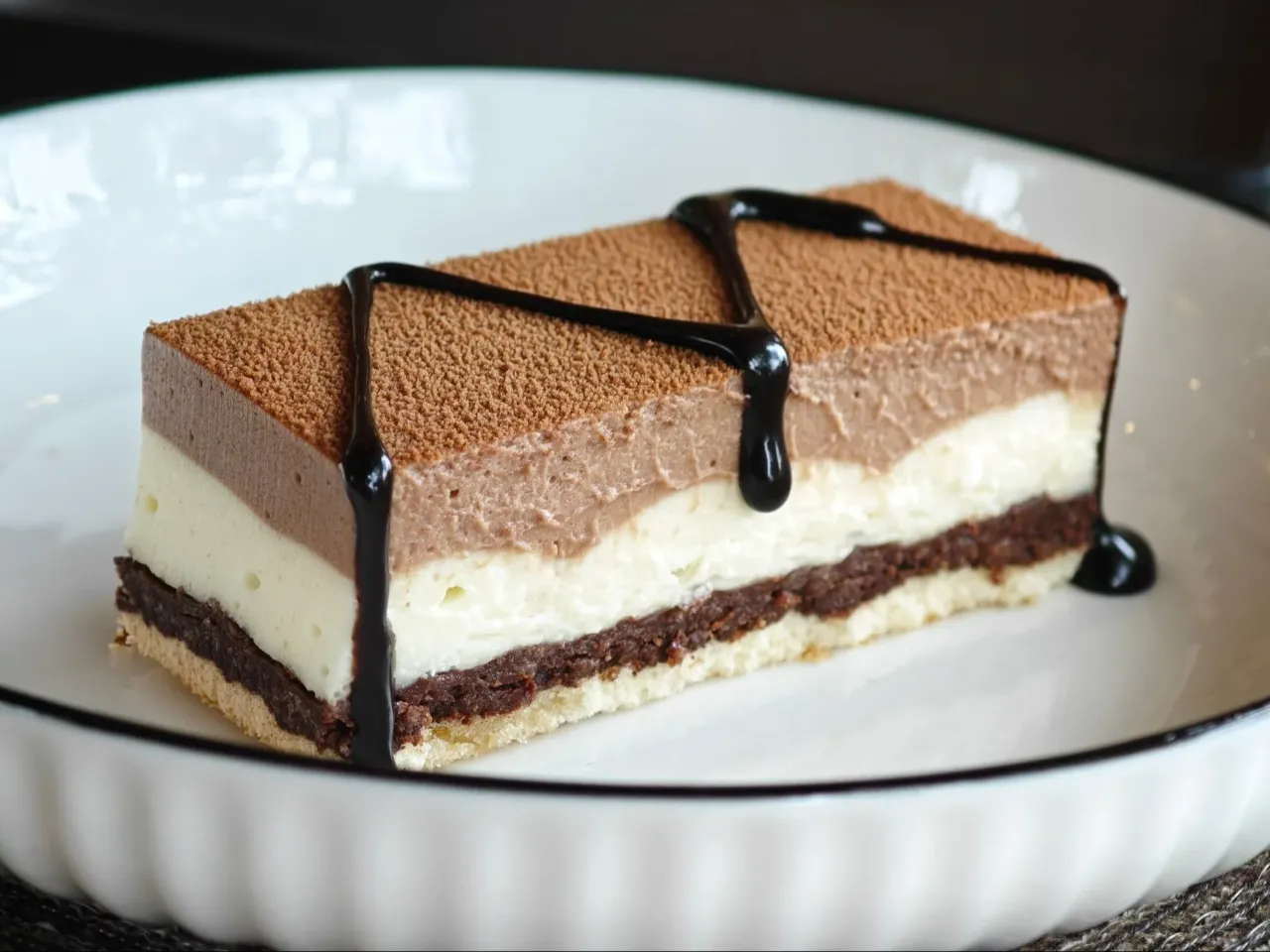 Pyszny deser z trzema warstwami musu: czekoladowego, śmietankowego i kawowego, posypany kakao i polany czekoladą. Idealny, co na deser zamiast ciasta.