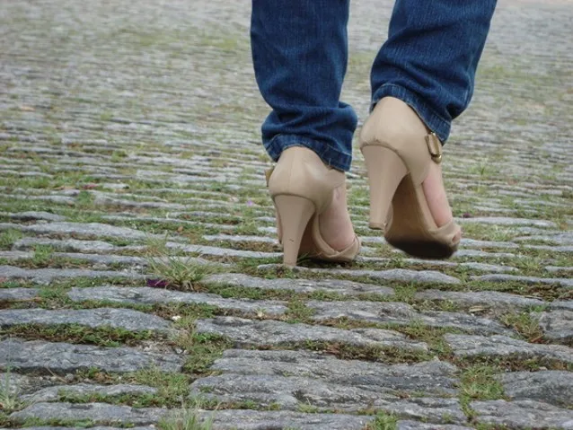 kobieta idąca na obcasach po kostce brukowej