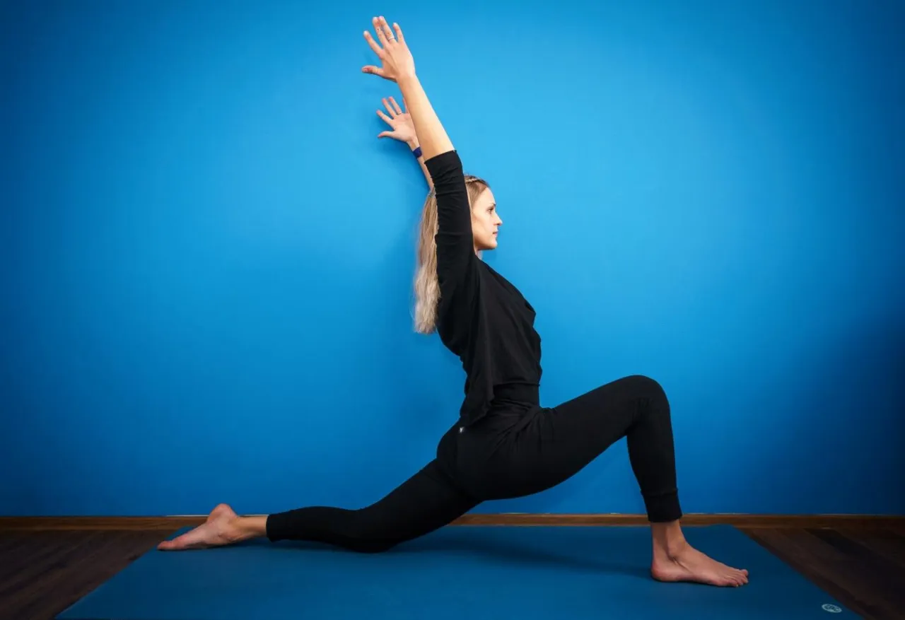 Dziewczyna rozciągająca się do szpagatu, uśmiechnięta, na macie jogowej