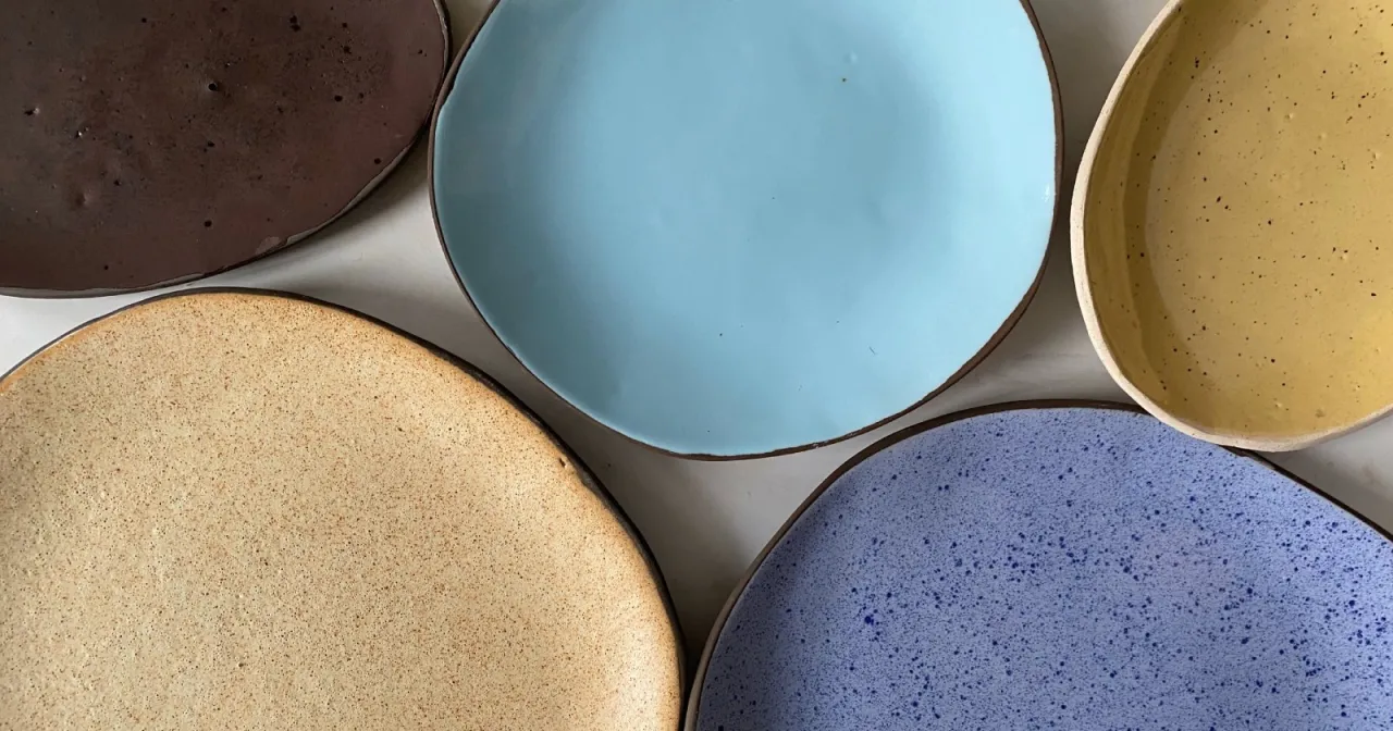 Pięć talerzy z ceramiki w r&oacute;żnych kolorach: brązowy, błękitny, ż&oacute;łty, beżowy i fioletowy.