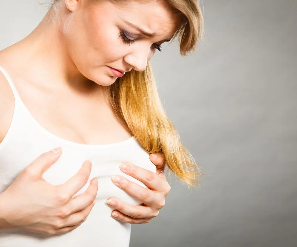 kobieta zmartwiona b&oacute;lem piersi, kobieta dotykająca piersi, kobieta myśląca o zdrowiu