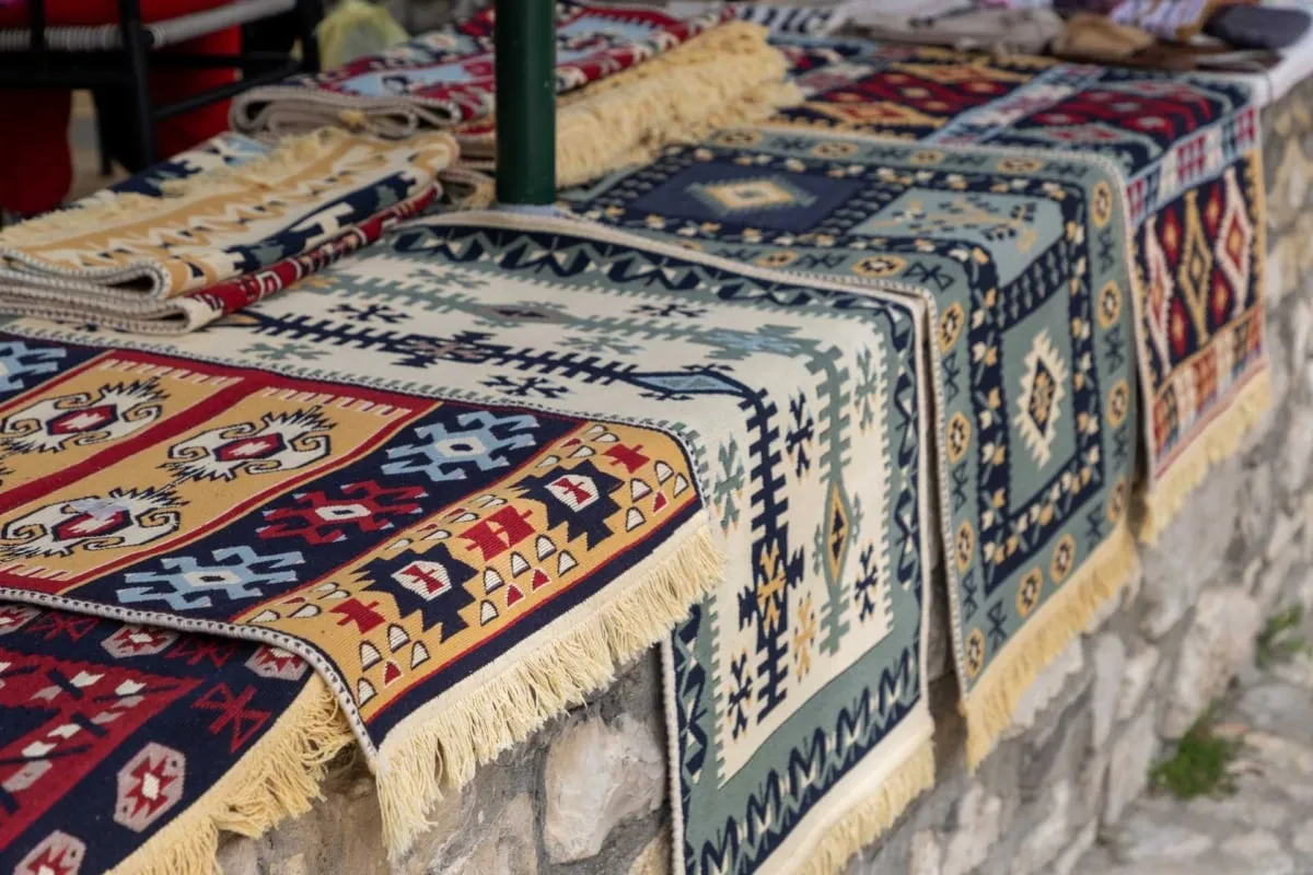Kolorowe, tradycyjne kilimy z frędzlami. Idealne pamiątki, kt&oacute;re warto przywieźć z Albanii.
