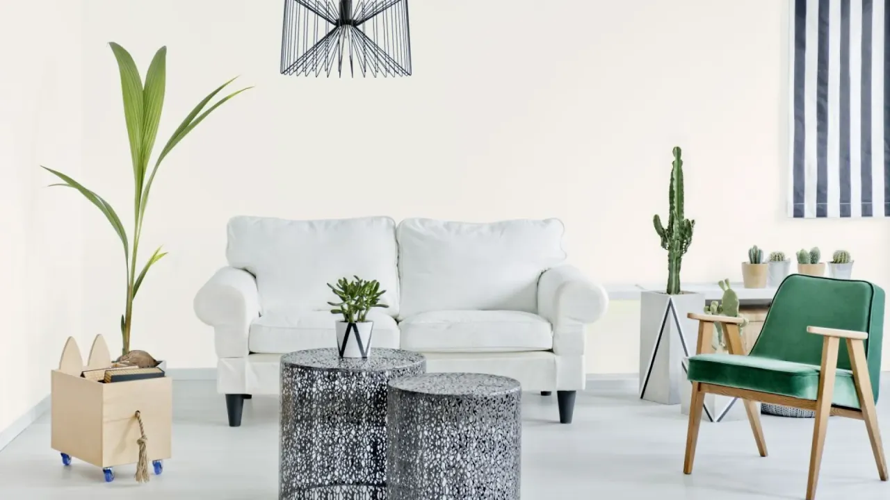 Jasne, przytulne wnętrze z białą kanapą, zielonym fotelem i roślinami. Ściany w odcieniu beckers soft ecru tworzą ciepłą atmosferę.