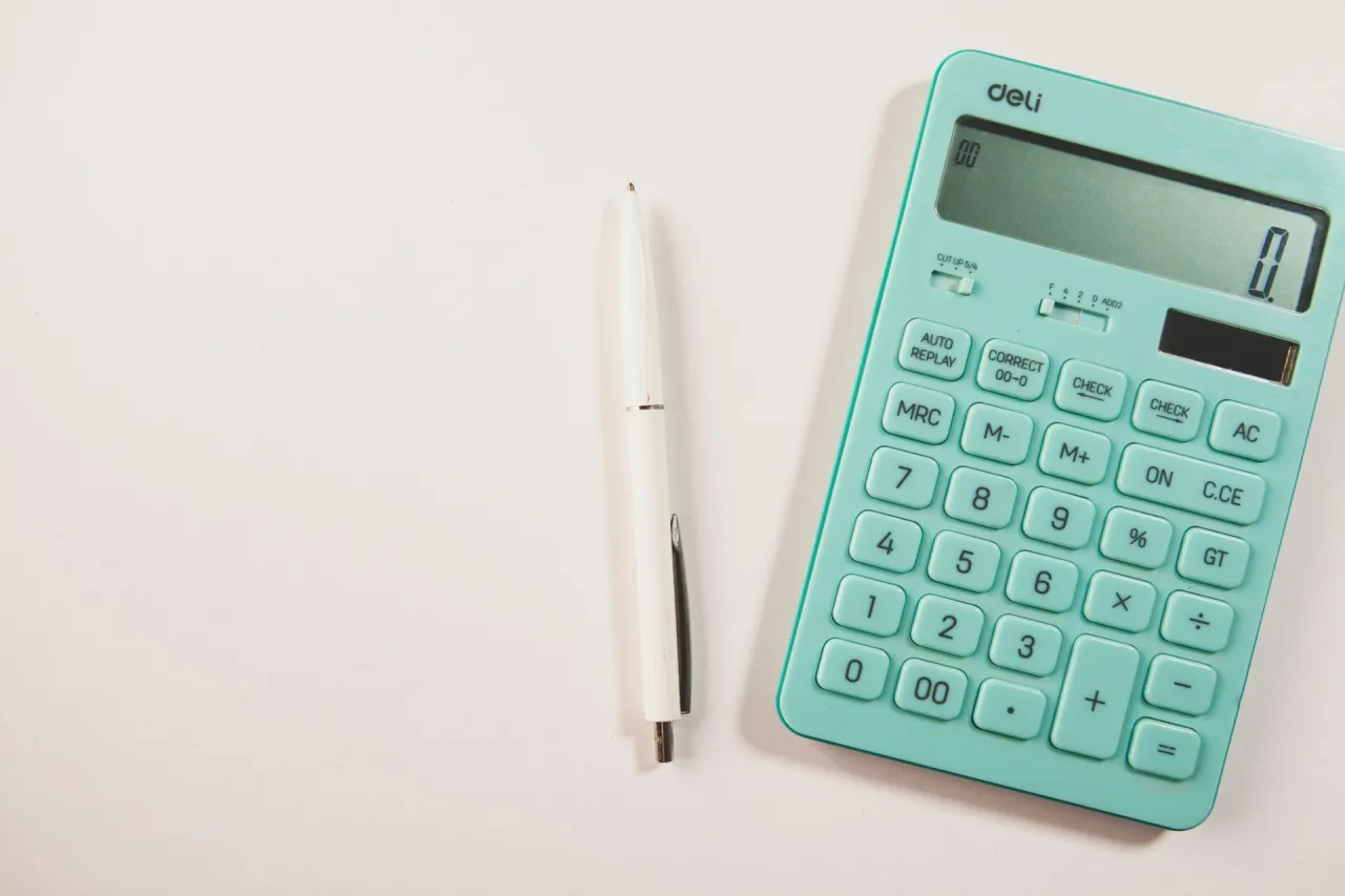 Miętowy kalkulator i biały długopis leżą na biurku, gotowe do pracy.