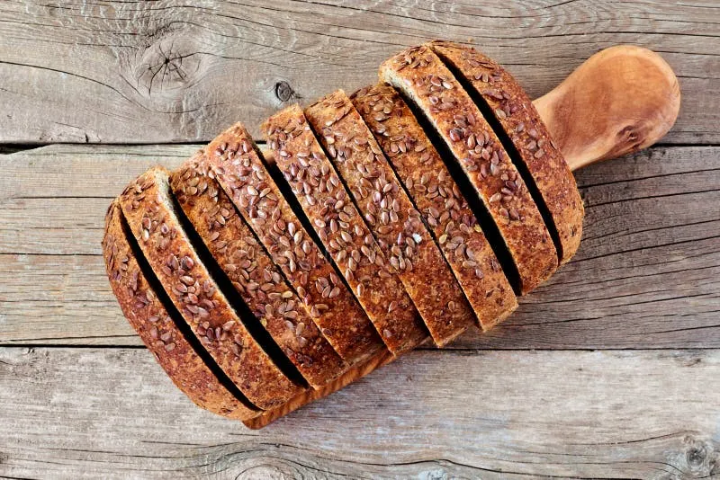 kawałki chleba razowego na drewnianej desce z miarką