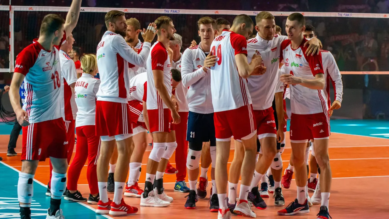 Drużyna siatkarzy w biało-czerwonych strojach świętuje sukces. To piękny przykład sportu amatorskiego, gdzie pasja i zaangażowanie są na pierwszym miejscu.