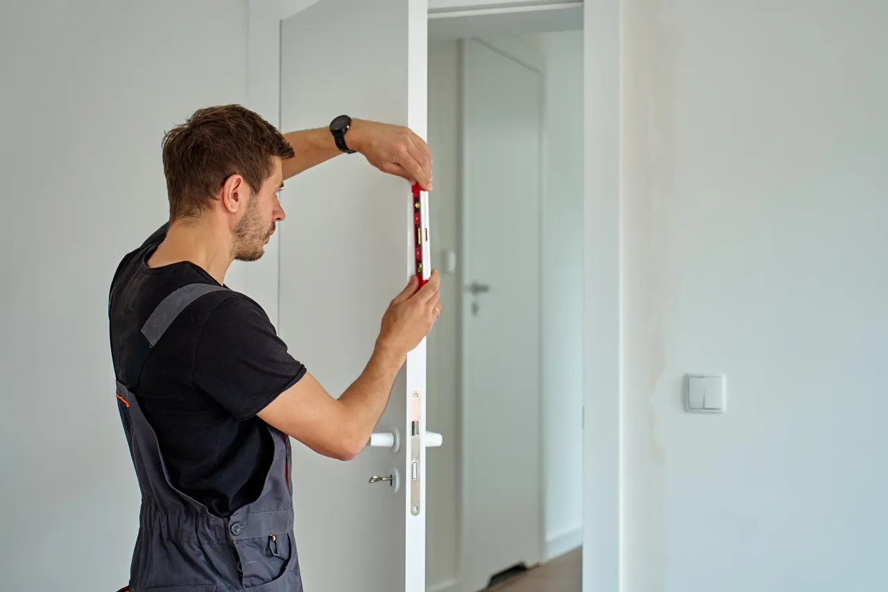Osoba regulująca zawias drzwi kluczem imbusowym