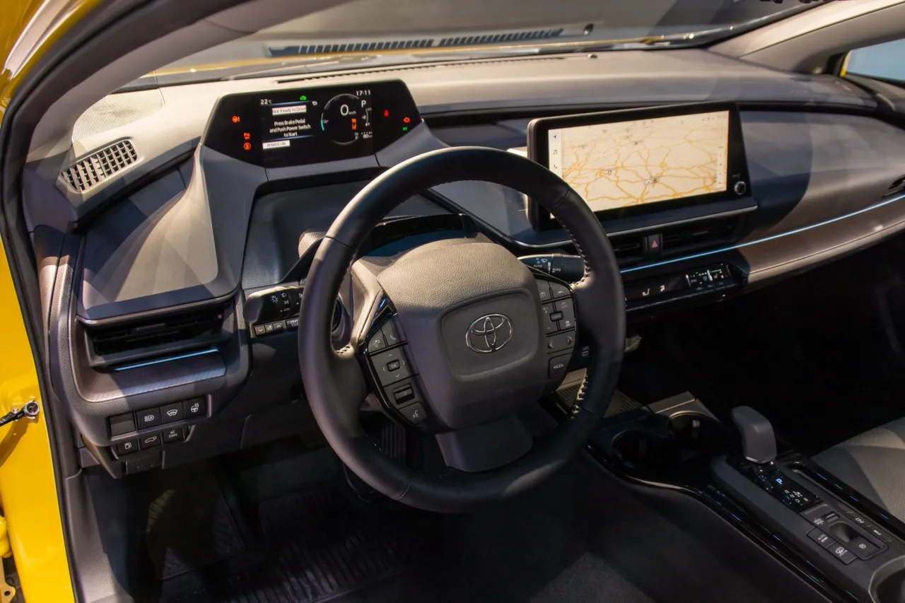 Wnętrze nowego Priusa w Polsce. Cyfrowe zegary, ekran nawigacji i kierownica z przyciskami.